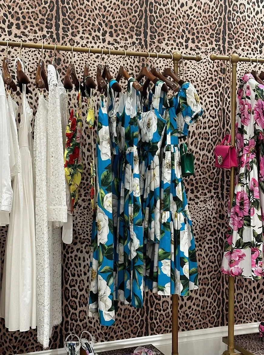 Colorful and elegant dresses displayed on a leopard print backdrop in a stylish boutique.